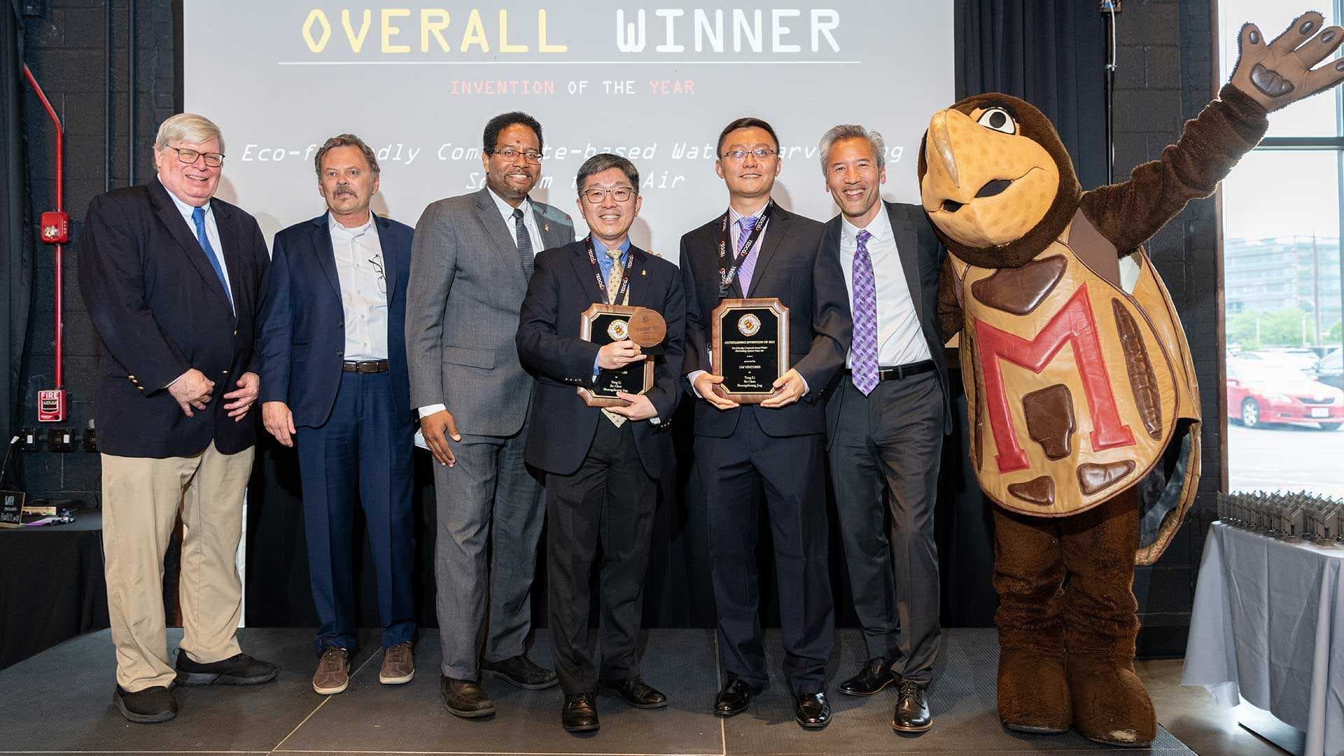 UMD Vice President for Research Gregory F. Ball, UM Ventures, College Park Director Ken Porter, President Darryll J. Pines, Invention of the Year overall winners Professor Teng Li and postdoctoral researcher Bo Chen, Interim Chief Innovation Officer Dean Chang and Testudo celebrate Tuesday at Innovate Maryland