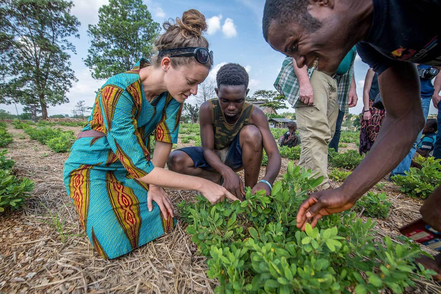 Instructors and students work in a garden bed of lush plants